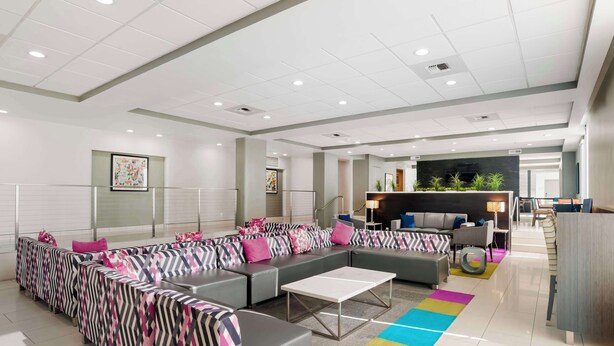 A modern hotel lobby with a large sectional sofa, a reception desk, and a dining area. - Best Western Plus Commerce Hotel (Los Angeles)