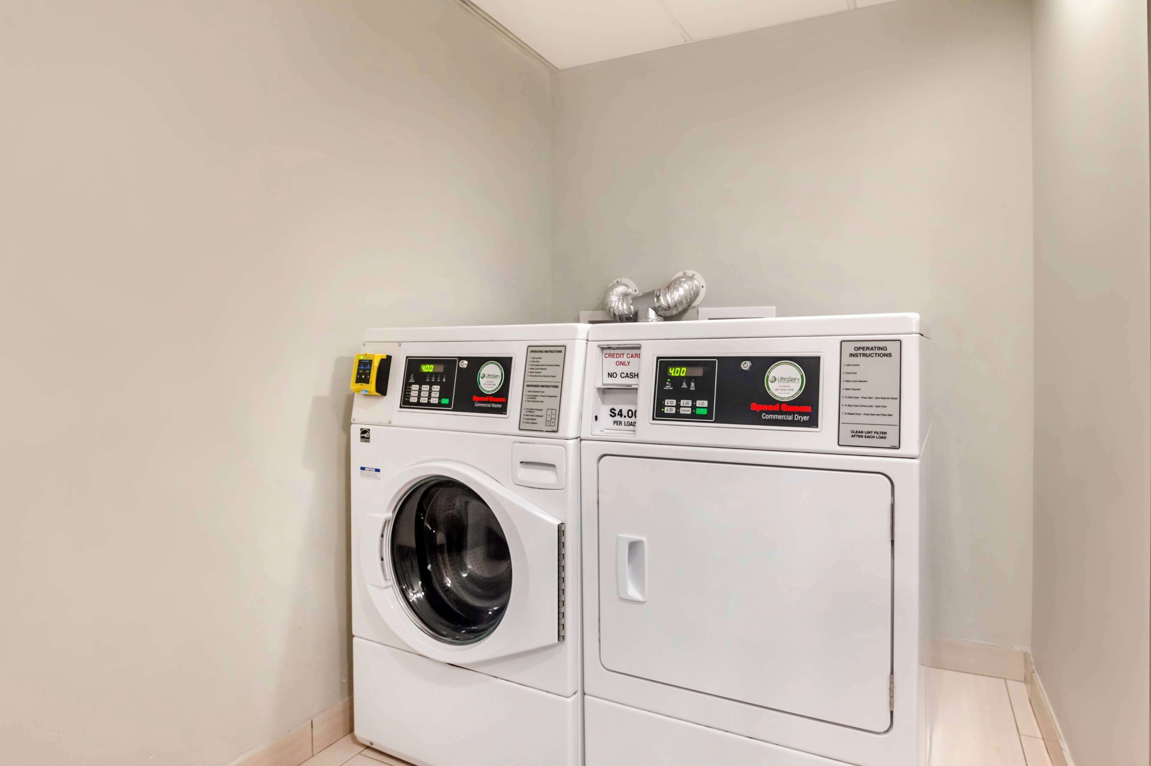 A laundry room with two white front-loading washing machines and a dryer.