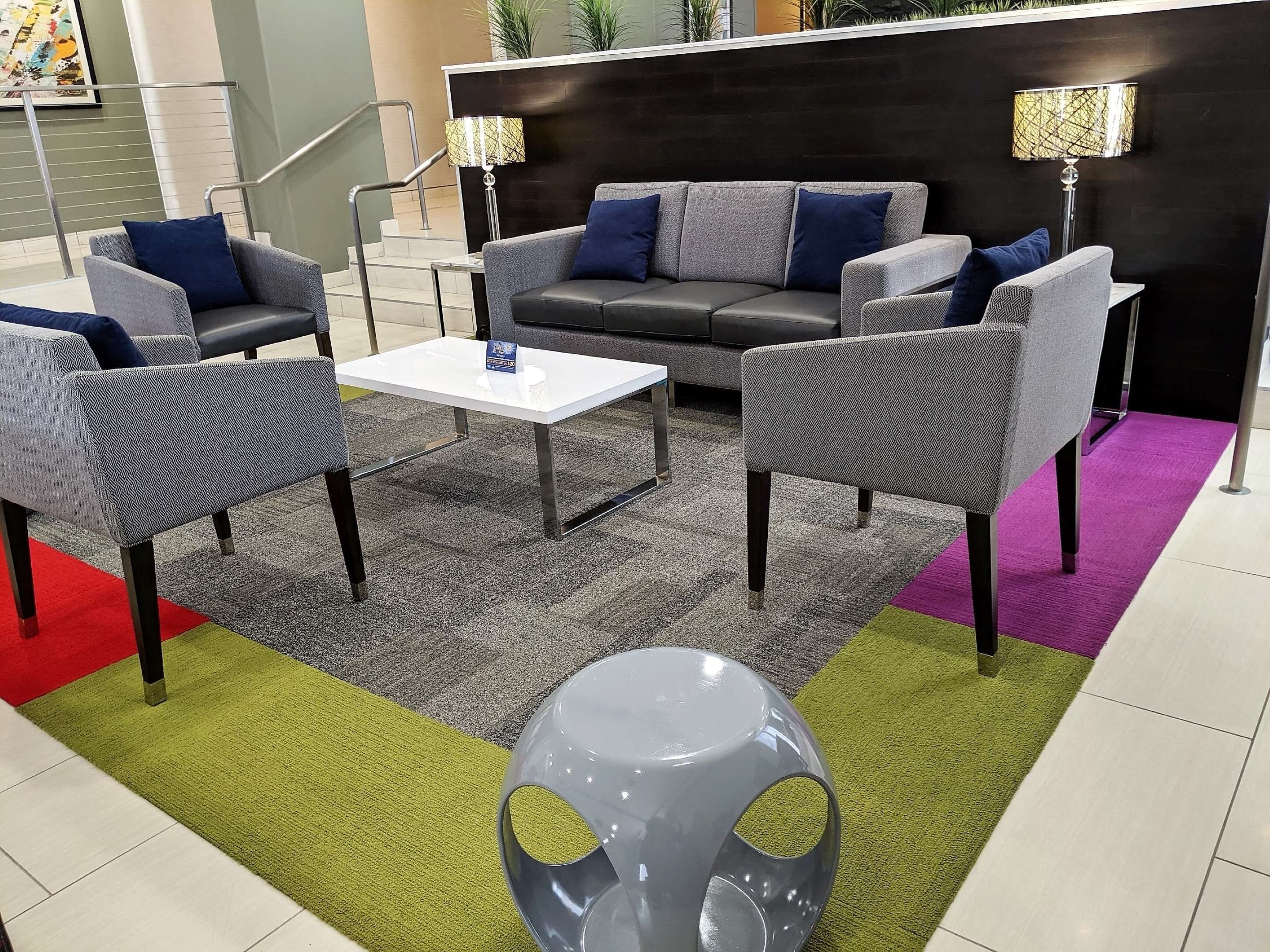 A modern lobby with a grey sofa set, a white coffee table, and a unique grey spherical chair.