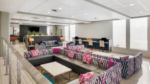 A modern hotel lobby with a sectional sofa, a reception desk, and large windows. - Best Western Plus Commerce Hotel (Los Angeles)