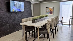 A conference room with a long table, chairs, a TV on the wall, and a large window. - Best Western Plus Commerce Hotel (Los Angeles)