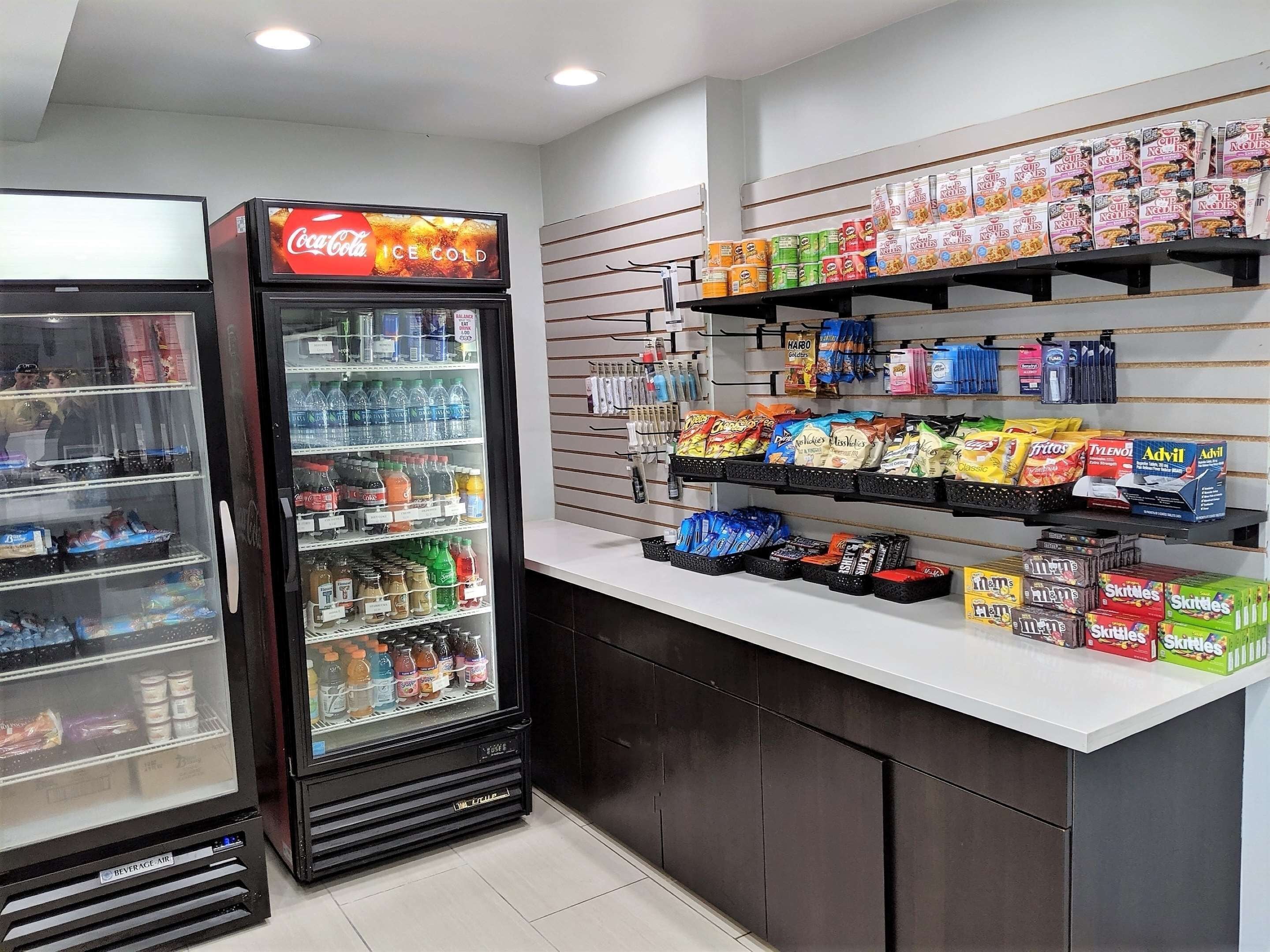 Un refrigerador ple de begudes diverses, una vitrina amb llaminatures i crispetes, i un congelador de Coca-Cola.