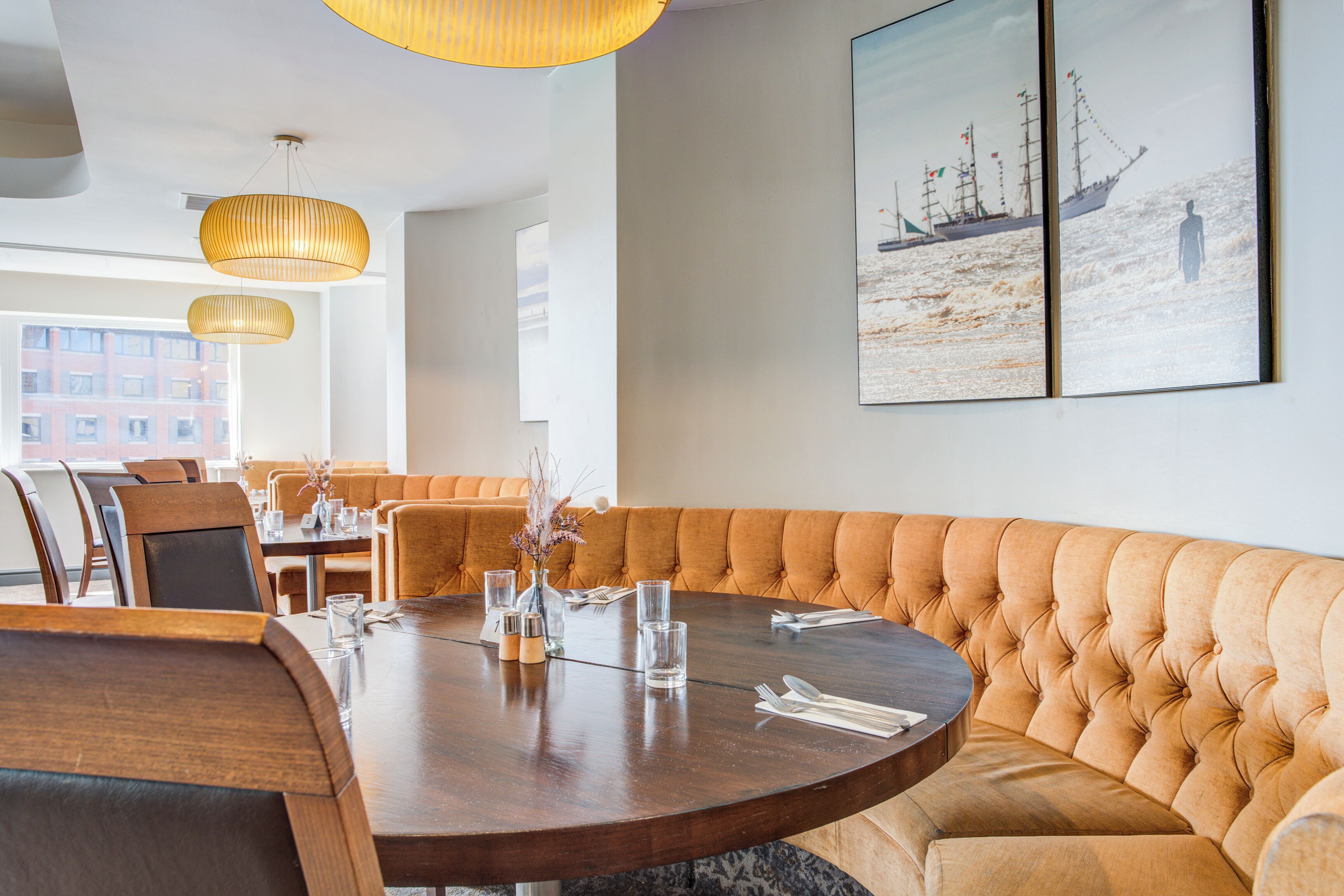 Een moderne eethoek met een ronde tafel, comfortabele zitplaatsen en hanglampen.