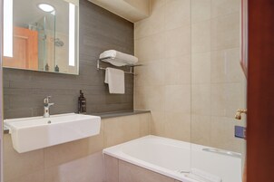 Un baño moderno con lavamanos, espejo y bañera.