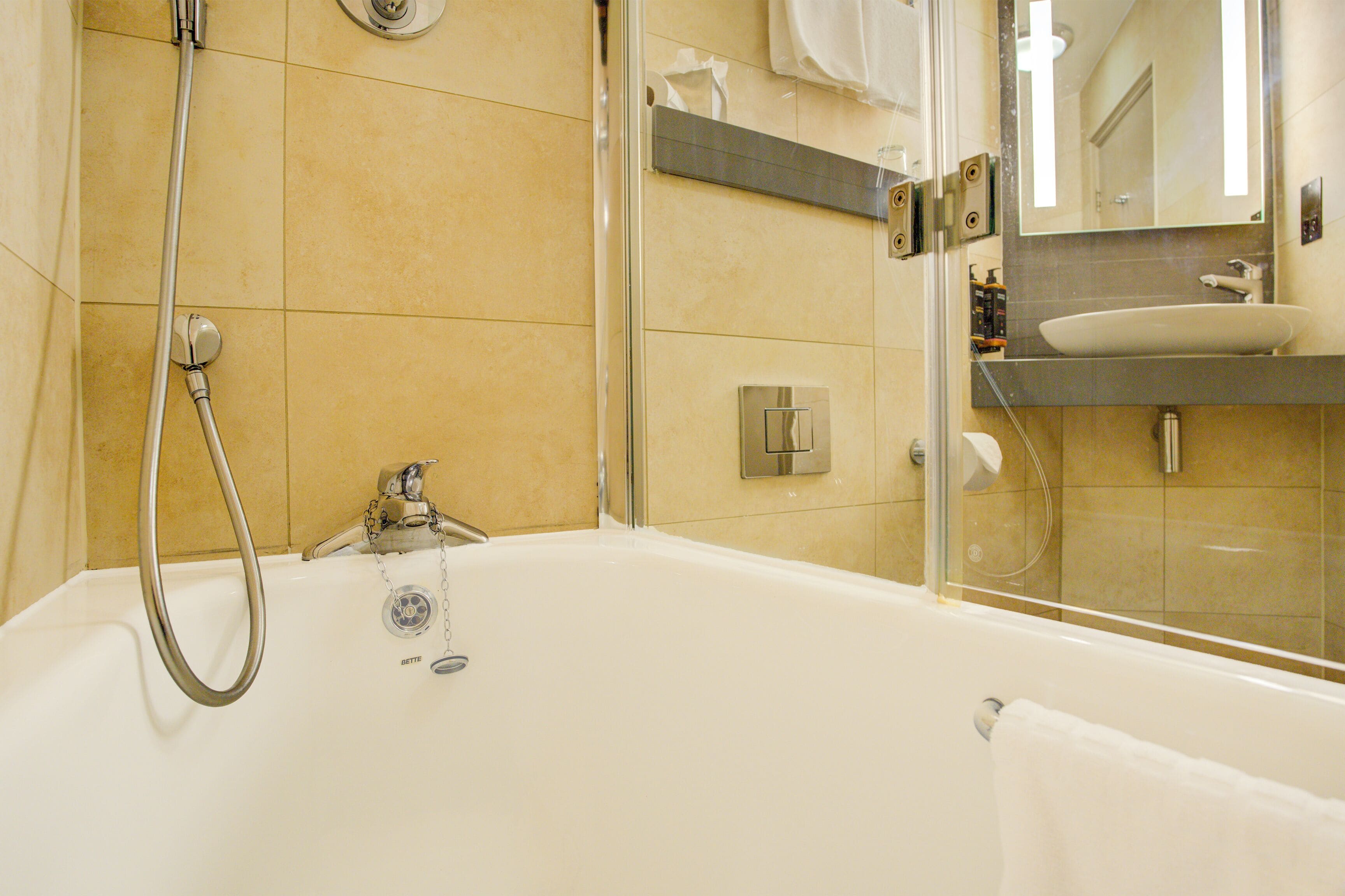 A modern bathroom with a bathtub, shower, and a vanity with a sink.