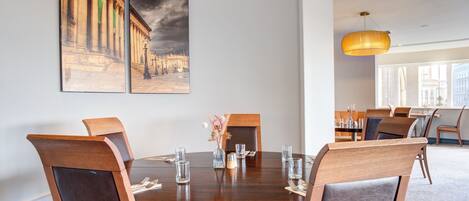Un'area pranzo con un tavolo rotondo, sedie e due quadri appesi al muro.
