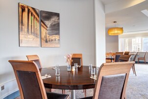 Un comedor con una mesa redonda, sillas y dos cuadros en la pared.