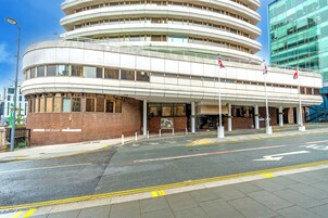 Un edificio de varios pisos con fachada curva, una entrada despejada y un letrero de 'KEEP CLEAR' en la acera.