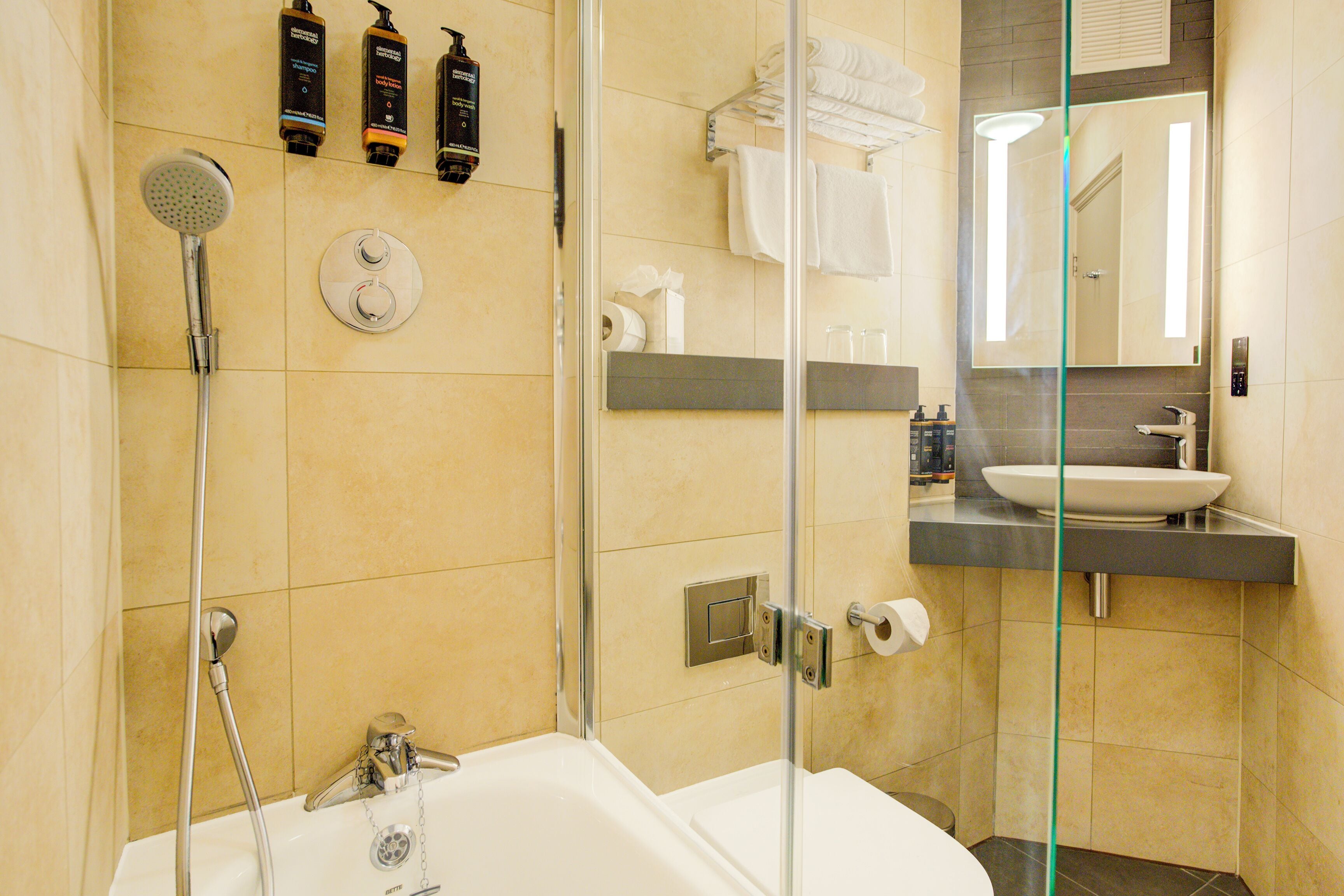 A modern bathroom with a glass-enclosed shower, a bathtub, a sink, and a mirror.