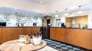 A reception area with a wooden reception desk, a digital screen, and a wall decorated with bird silhouettes.