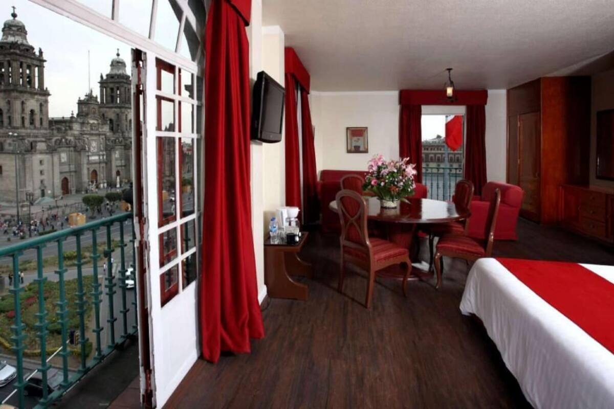 A hotel room with a balcony, a dining area, and a bed.