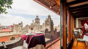 A terrace with a table set for two, overlooking a historic building with domes and intricate architecture. - Best Western Majestic (Mexico City)