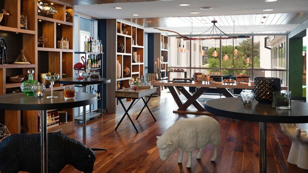 A modern interior with wooden shelves, tables, and a unique sheep sculpture. - Renaissance Minneapolis Bloomington Hotel (Bloomington)