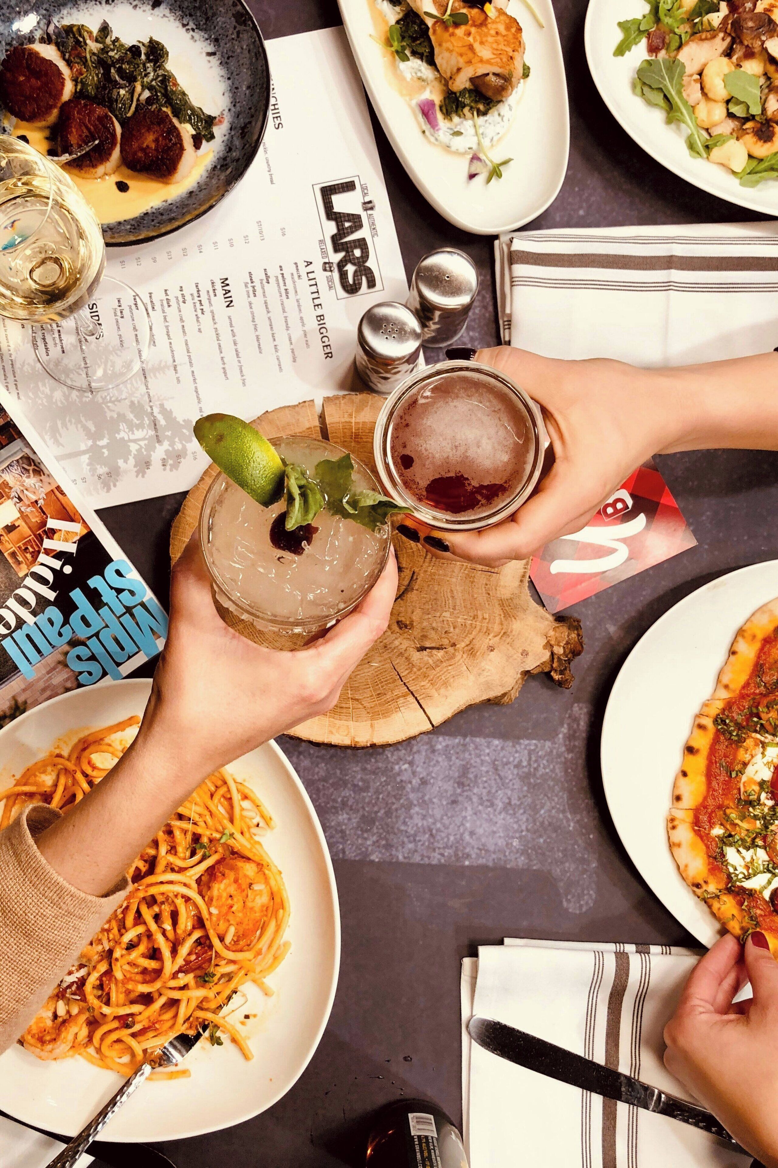 A table with various dishes, a menu, and a drink with a lime garnish.