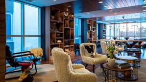 A modern interior with wooden floors, large windows, and a variety of seating options including fluffy chairs and a sofa. - Renaissance Minneapolis Bloomington Hotel (Bloomington)