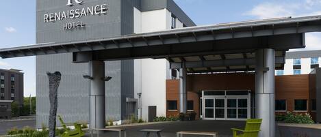 The exterior of the Renaissance Hotel with a covered entrance, outdoor seating, and a water feature.