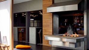 A modern bar area with a central fire feature, seating, and a visible bar stocked with bottles. - Renaissance Minneapolis Bloomington Hotel (Bloomington)