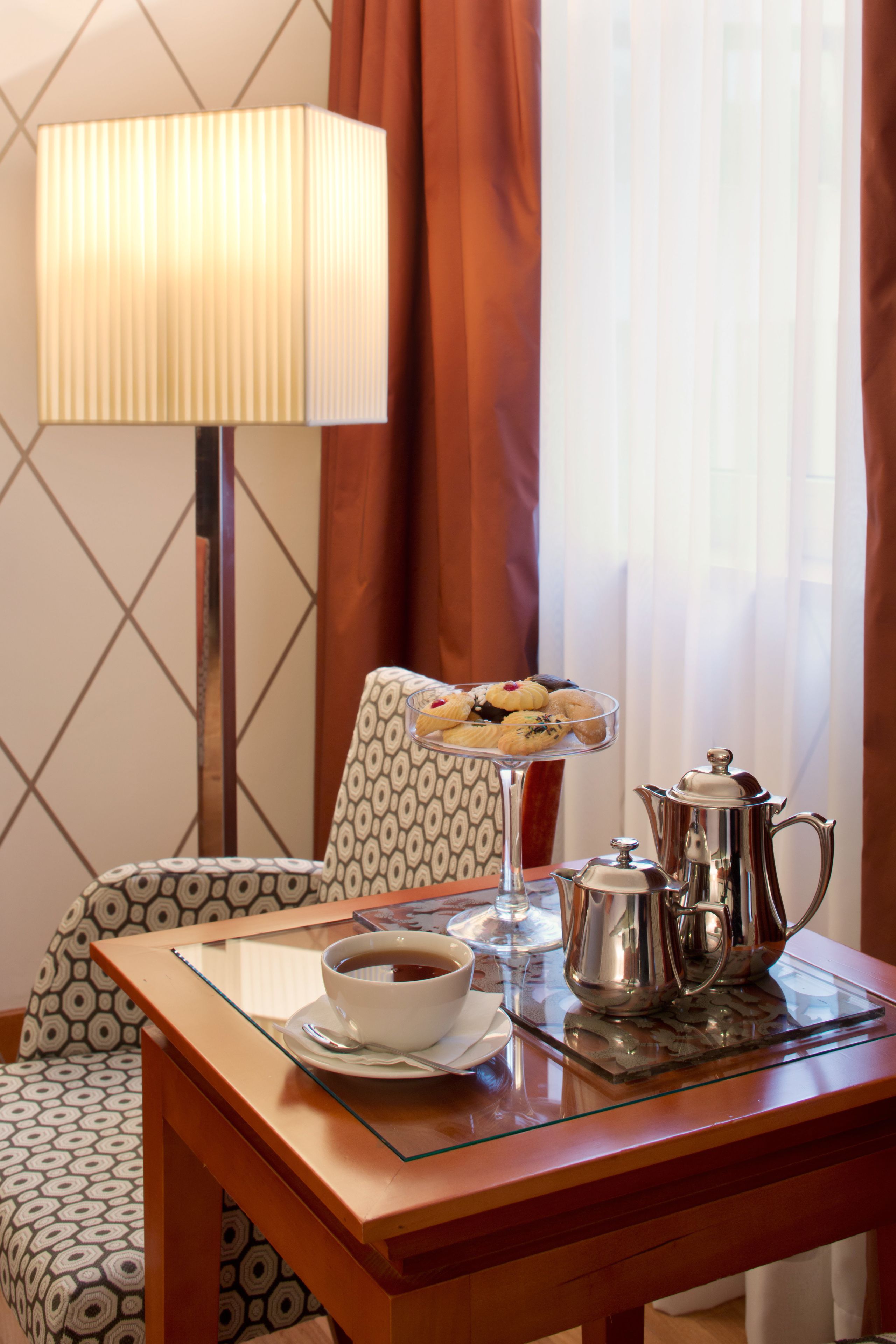 Una camera d'albergo con un tavolo apparecchiato per la colazione, che include una ciotola di zuppa, un bicchiere di succo, un vassoio di pasticcini e una caffettiera.