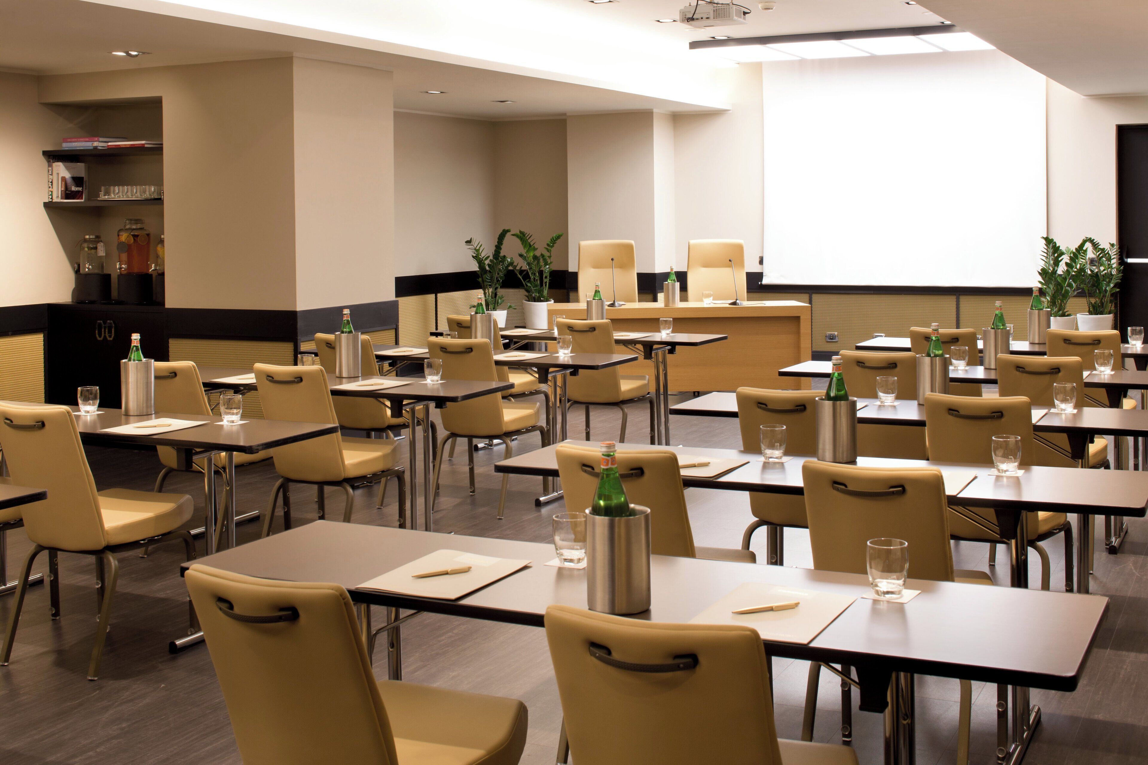A conference room with multiple tables and chairs, equipped with water bottles and notepads.