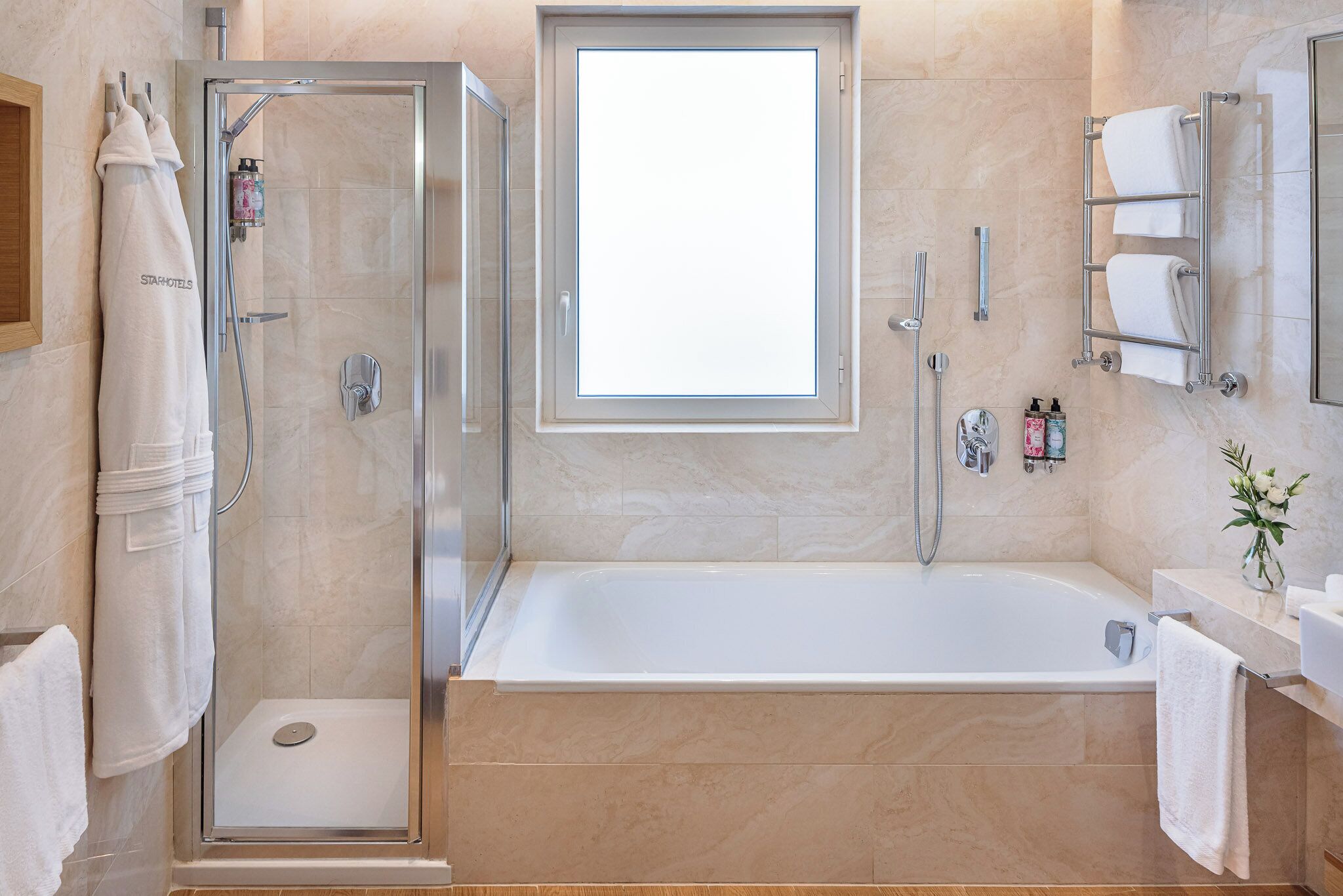 Un baño moderno con ducha de vidrio, una bañera grande y un ventanal sobre la bañera.