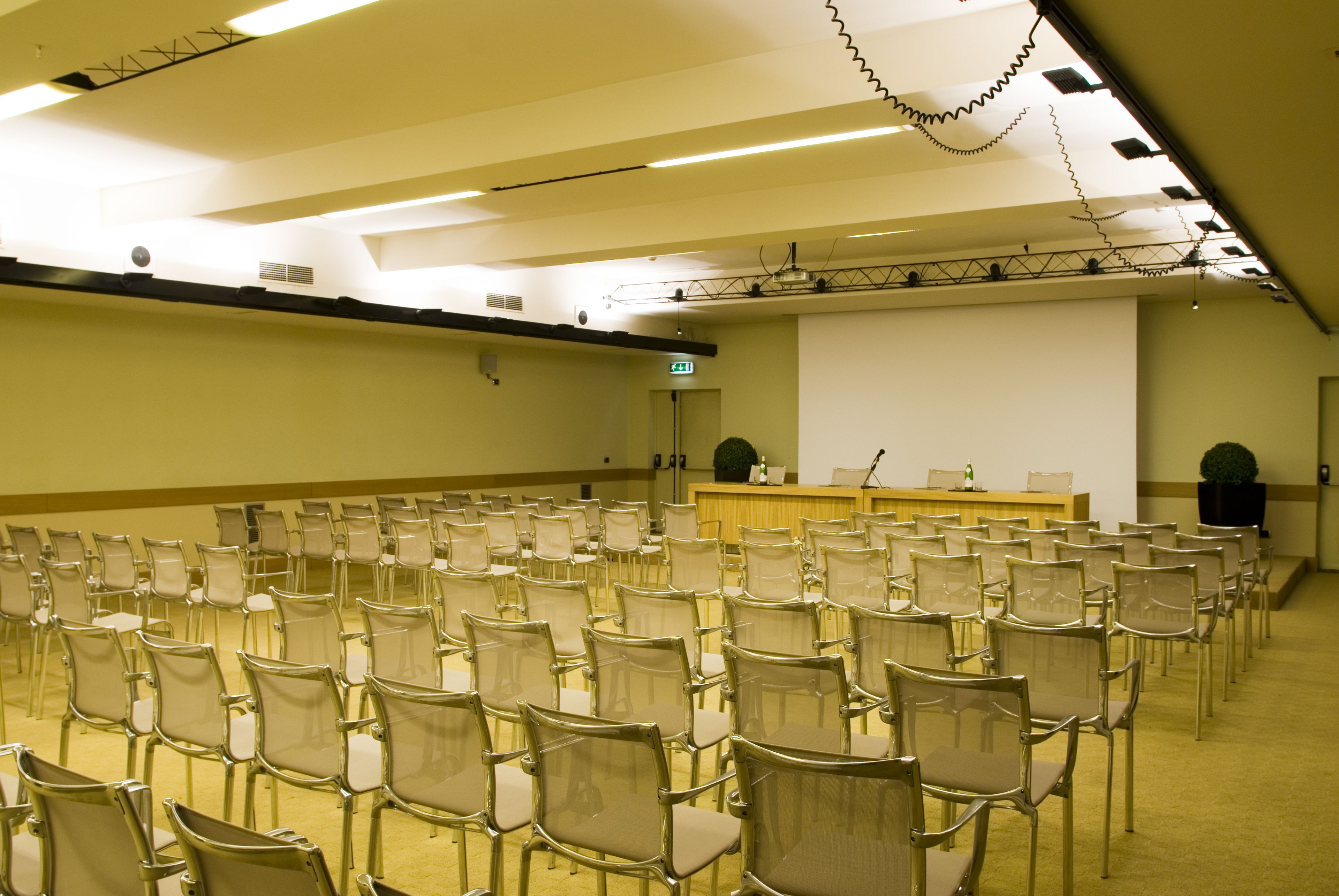 Ett konferensrum med rader av stolar, en talarstol och en projektorduk.