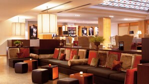 Un área de estar moderna con sofás, otomanas y una zona de bar con televisor y equipo de bar.