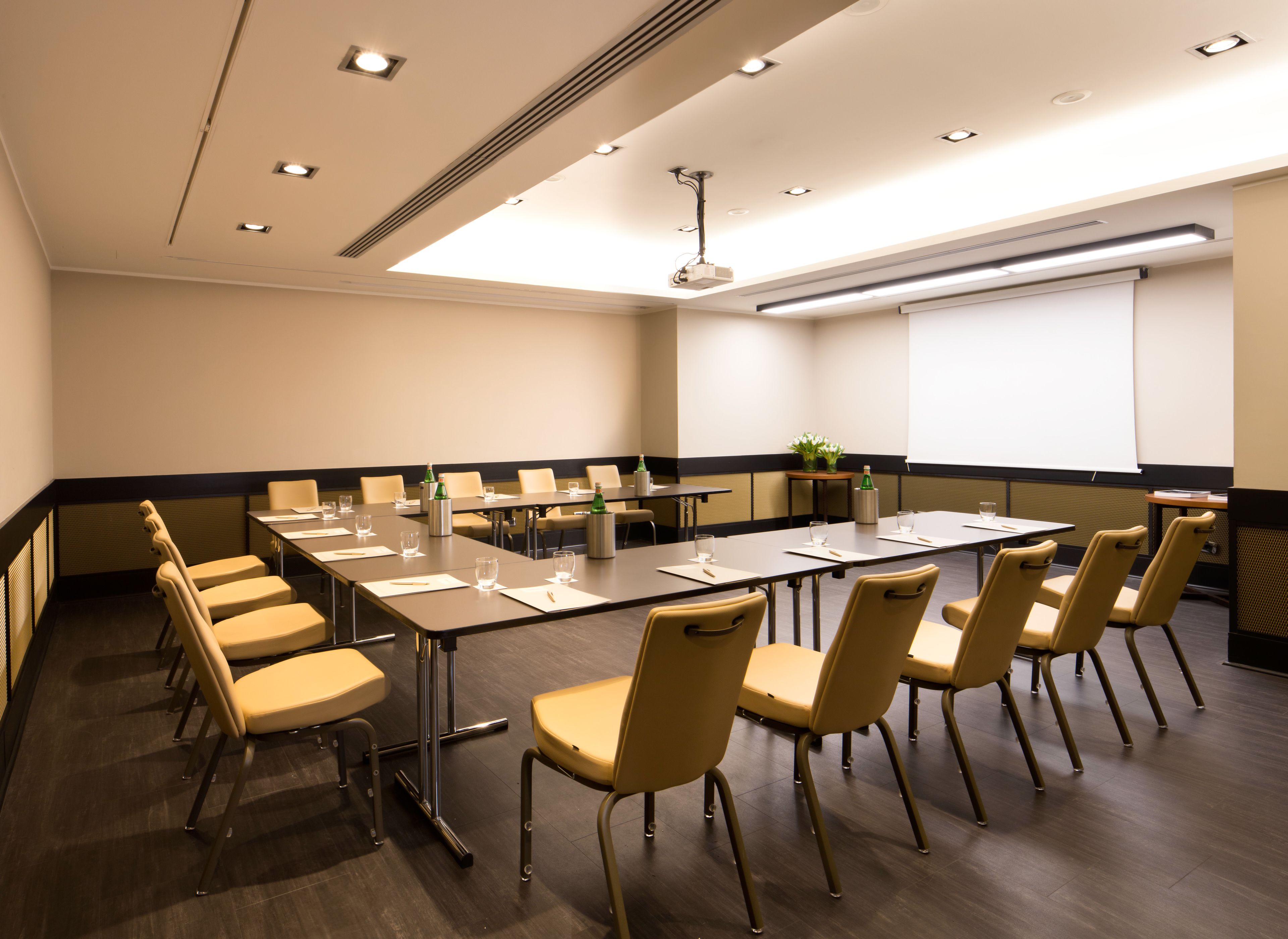 A conference room with a long table, chairs, a projector screen, and a whiteboard.