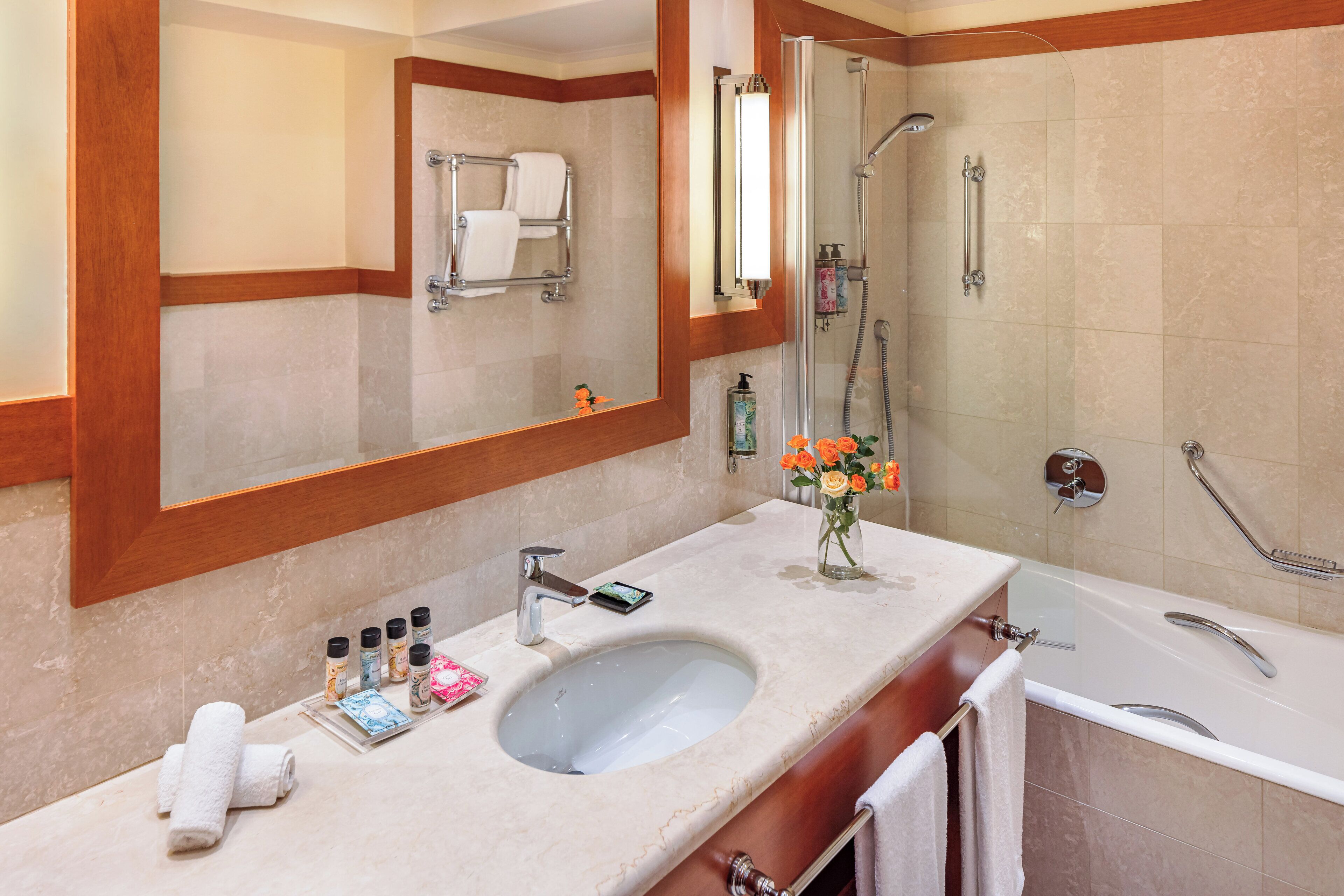 A bathroom with a large mirror, a sink, a shower, and a bathtub.