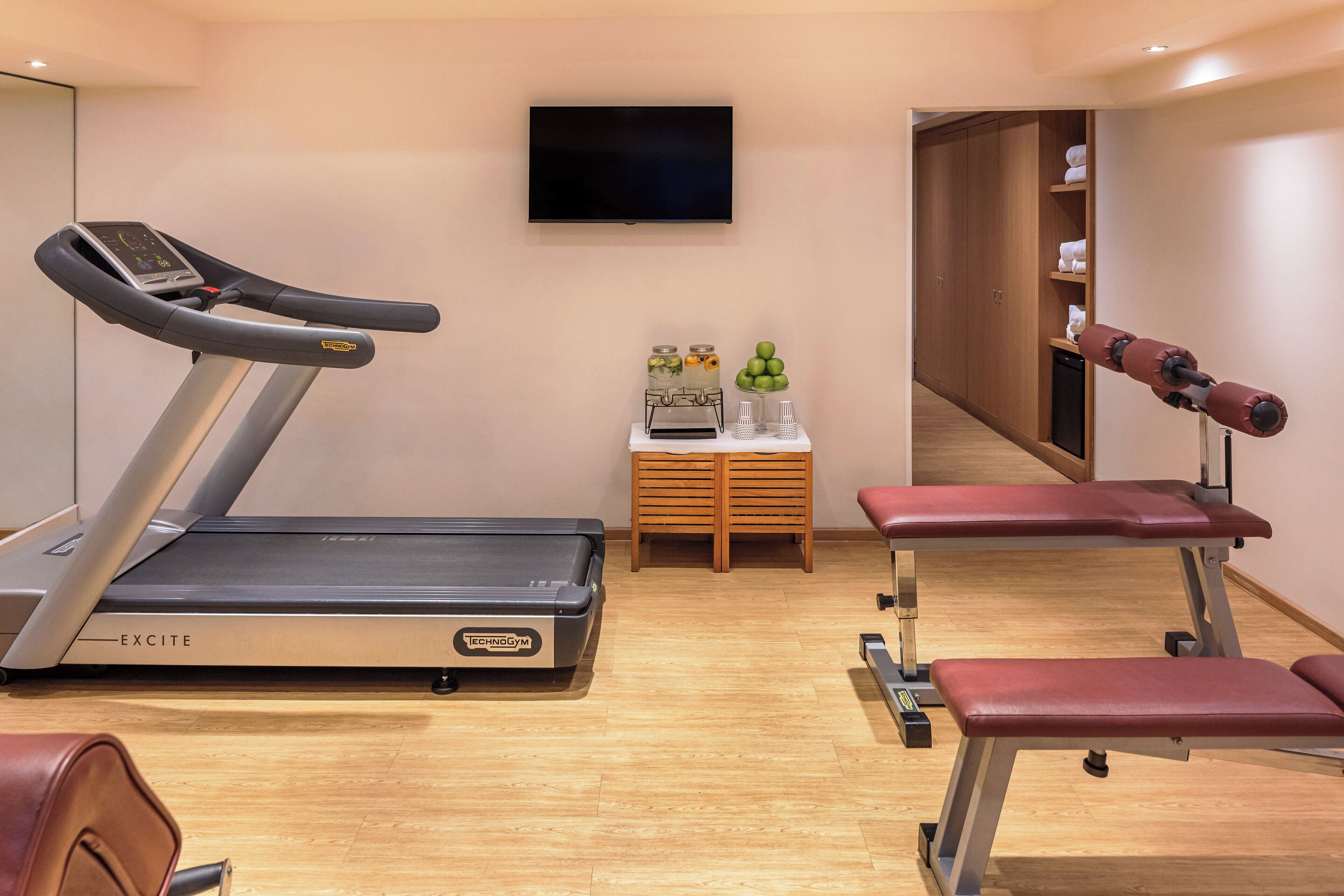 A gym with a treadmill, bench press, and weights.