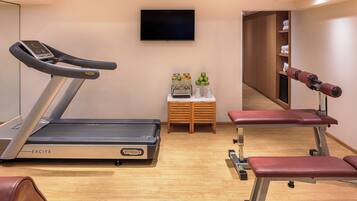 A gym with a treadmill, bench press, and weights.