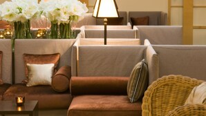 Un espacio lounge moderno con sofás, una lámpara y flores decorativas.