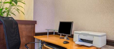 A wooden desk with a computer, keyboard, and printer.