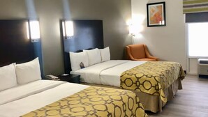Habitación de hotel con dos camas, una silla, una mesita de noche y una lámpara de pared.