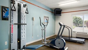 Un gimnasio de hotel con una máquina TotalBody, un stepper y una cinta de correr.