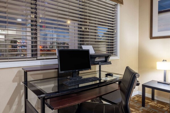 A modern office desk with a computer, keyboard, and chair.