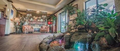 A spacious room with a large window, a chandelier, and a small indoor waterfall feature.