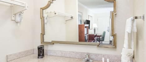 Une salle de bain avec un comptoir en granit, un lavabo blanc, un grand miroir et un porte-serviettes.