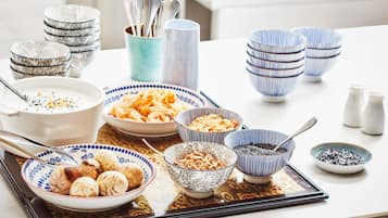 Una mesa de comedor con varios cuencos y platos de comida, incluyendo un tazón de sopa, un plato de dumplings y un cuenco de nueces.