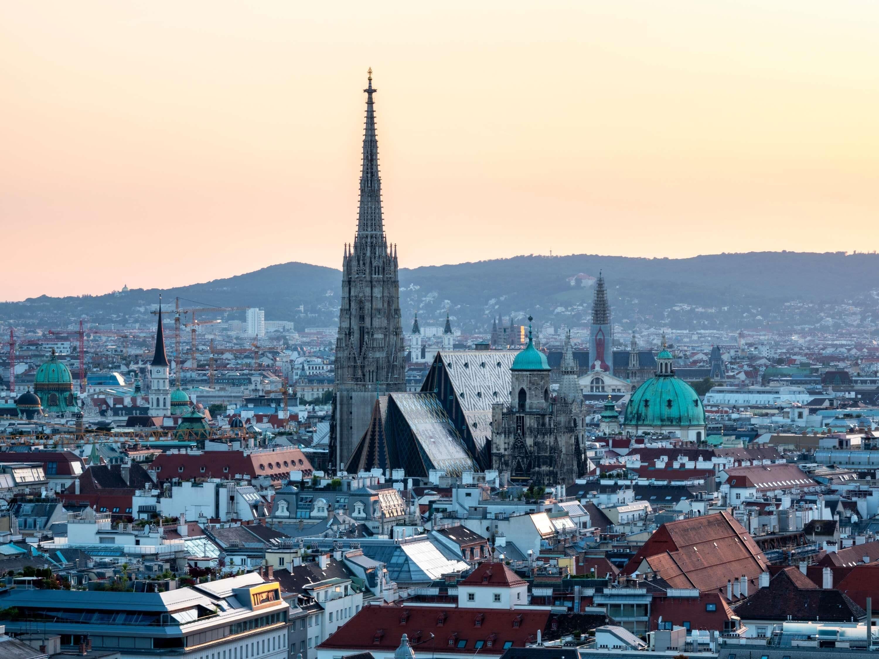 Et bybillede med en markant katedral, forskellige bygninger og fjerne bjergkæder.