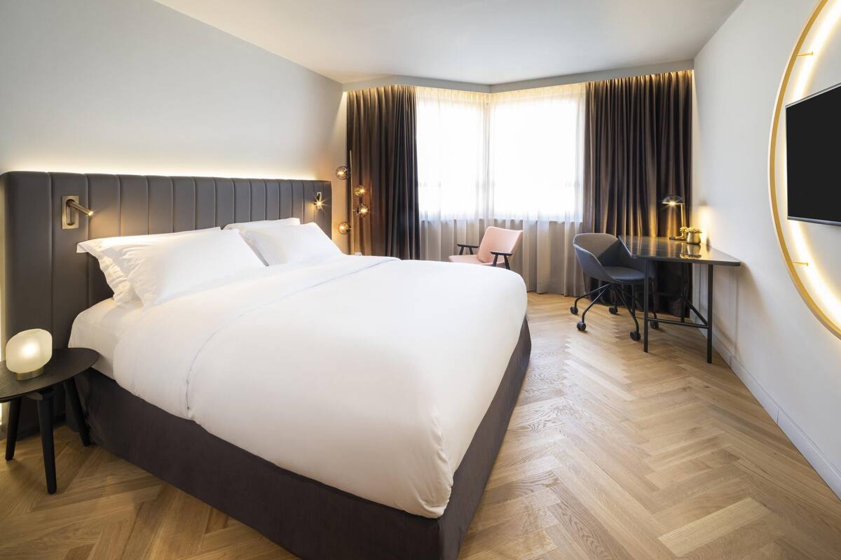 Hotellihuone, jossa on suuri sänky, työpöytä, tuoli ja televisio.