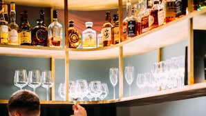 A bar area with shelves of liquor bottles and empty wine glasses. - Hotel Am Konzerthaus - MGallery Collection (Vienna)