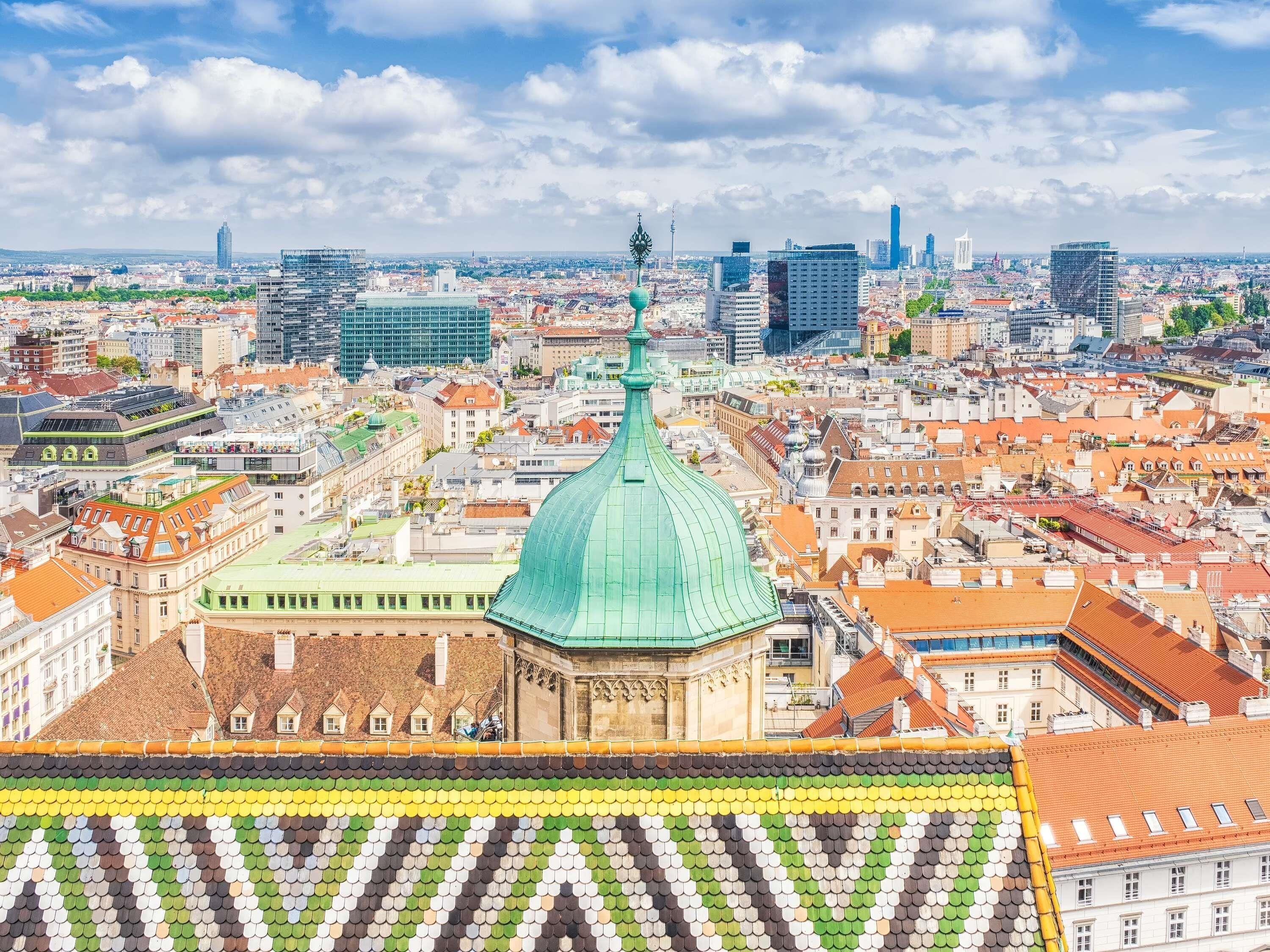 Une vue urbaine mettant en valeur un bâtiment remarquable, doté d’un toit végétalisé, d’un grand dôme et d’une tour horloge.