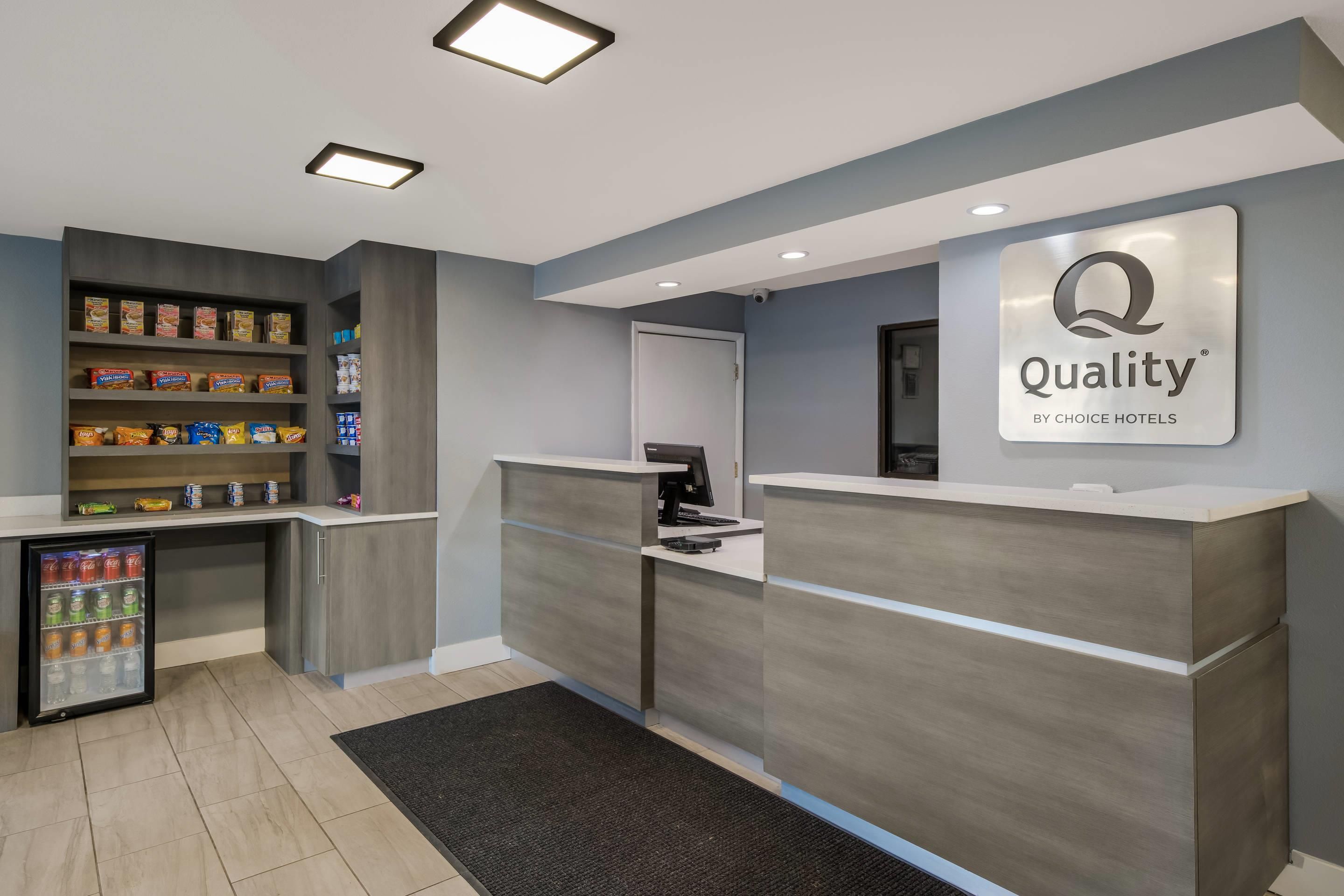 A reception area with a sign reading 'Quality' and a refrigerator stocked with beverages.