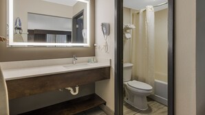 A bathroom with a sink, mirror, toilet, and shower.