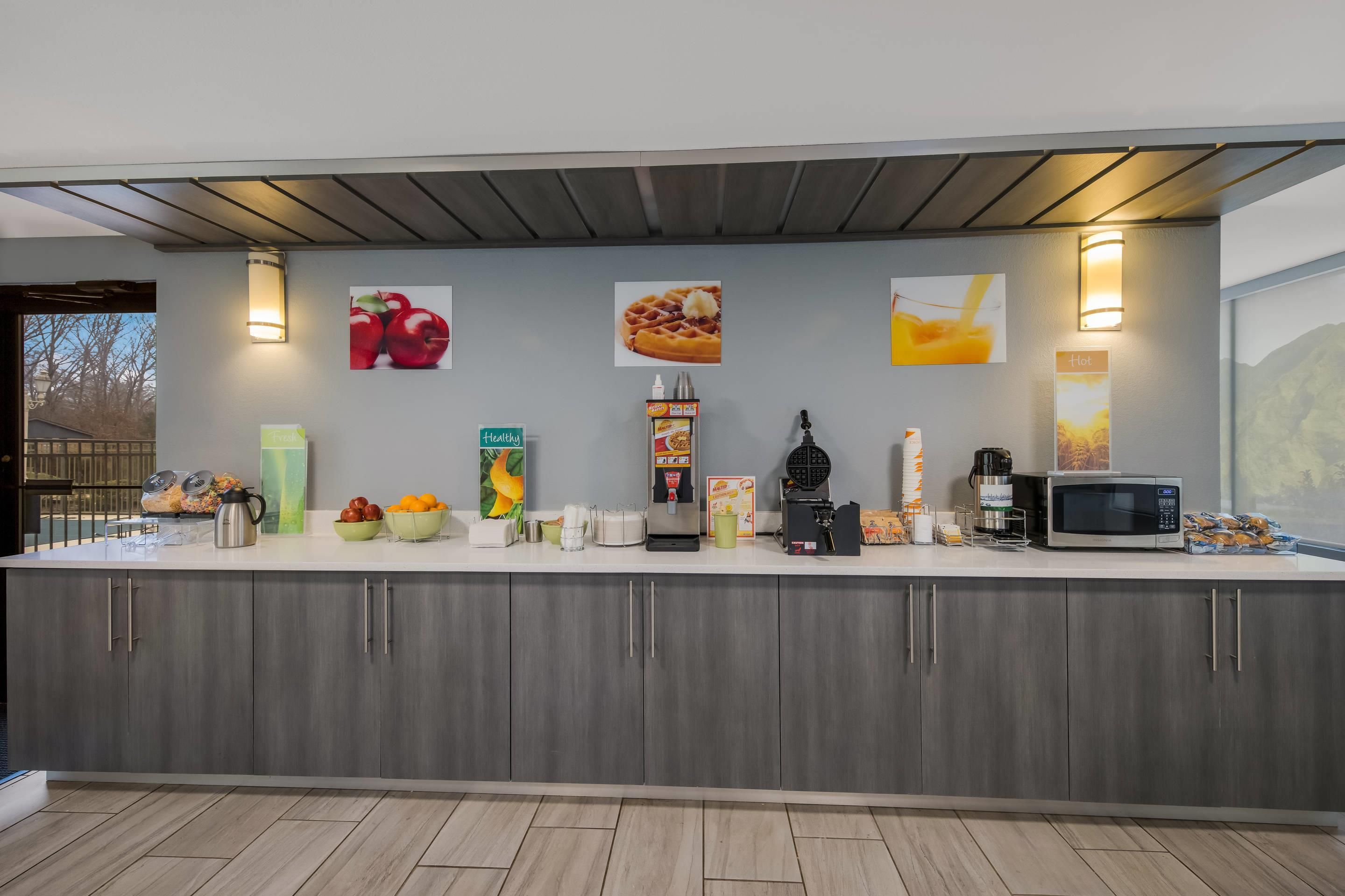 A modern kitchen with a white countertop, grey cabinets, and various food items and appliances.