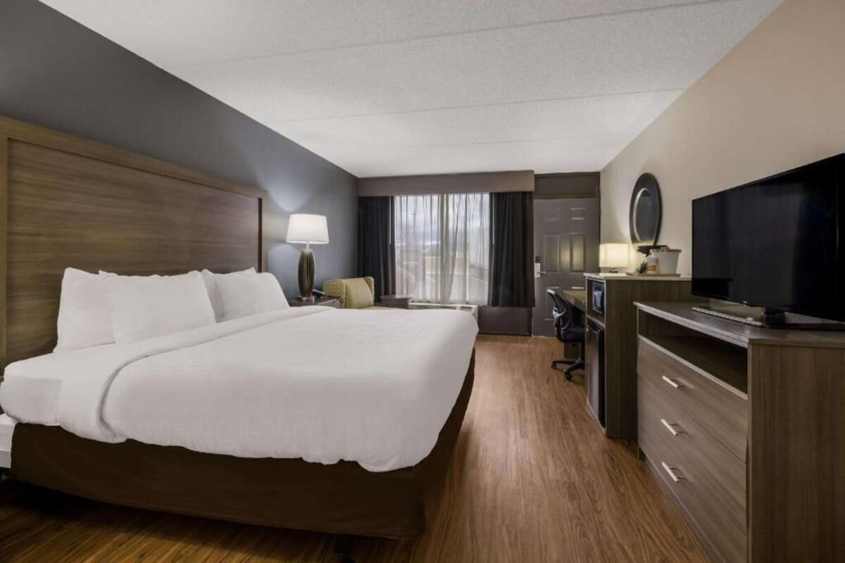 A hotel room with a large bed, a desk, a television, and a wardrobe.