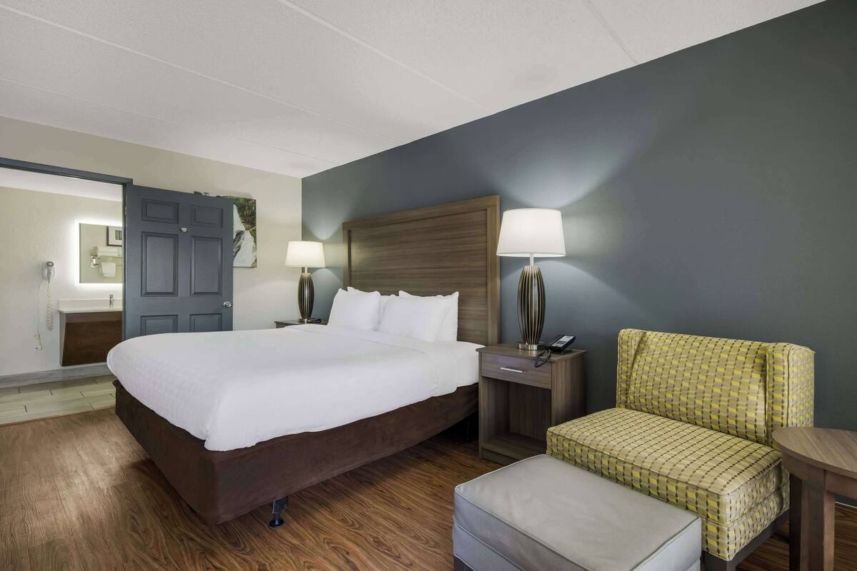A hotel room with a large bed, two bedside tables with lamps, a chair, and a small table.