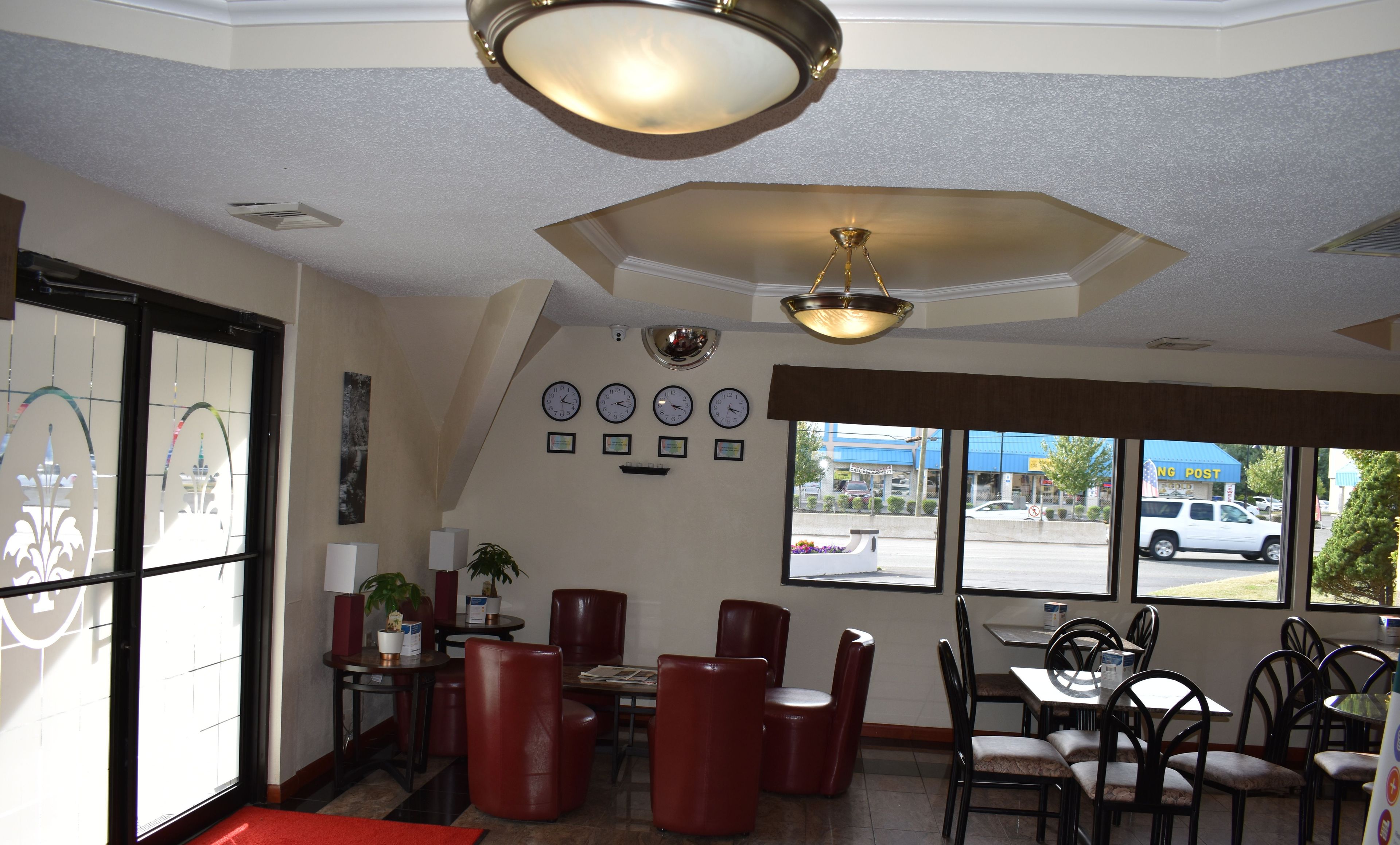 A restaurant interior with a dining area, chairs, tables, a ceiling light fixture, and a wall with clocks.