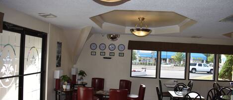 A restaurant interior with a dining area, chairs, tables, a ceiling light fixture, and a wall with clocks.