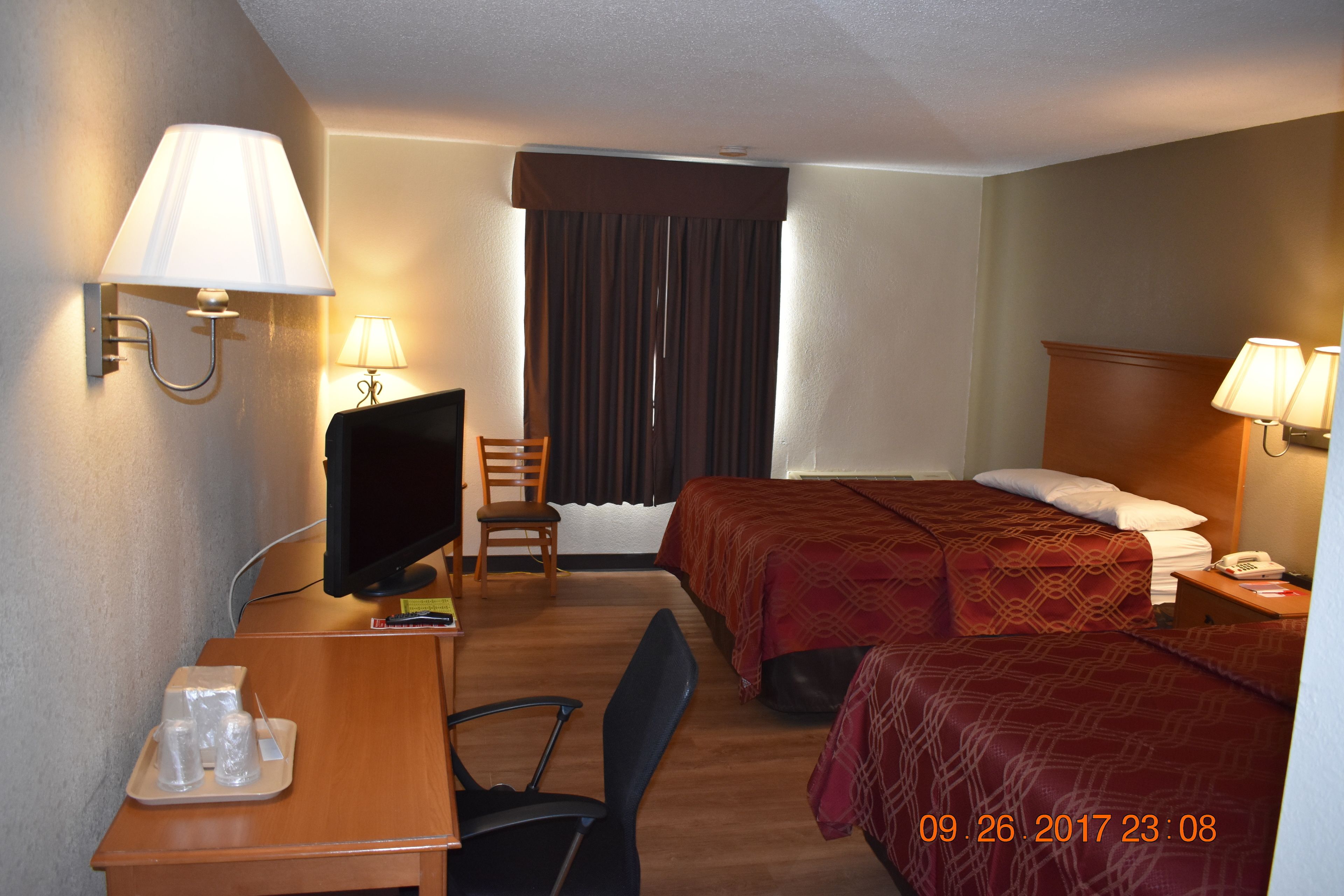 Ein Hotelzimmer mit zwei Betten, einem Schreibtisch mit Computer, einem Sessel, einem Fernseher und einem Telefon.